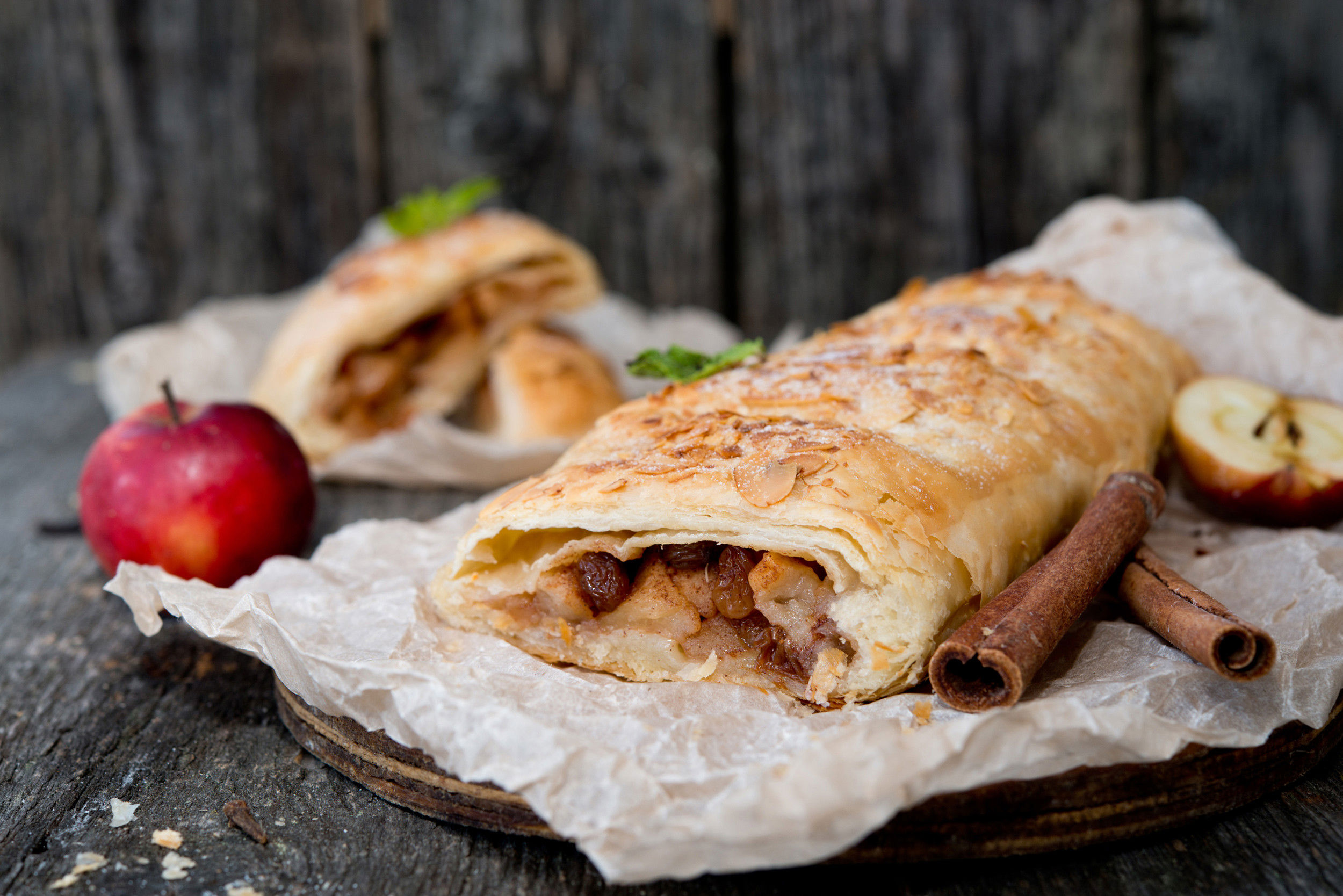 Apple strudel, decorated with cinnamon sticks and apples.