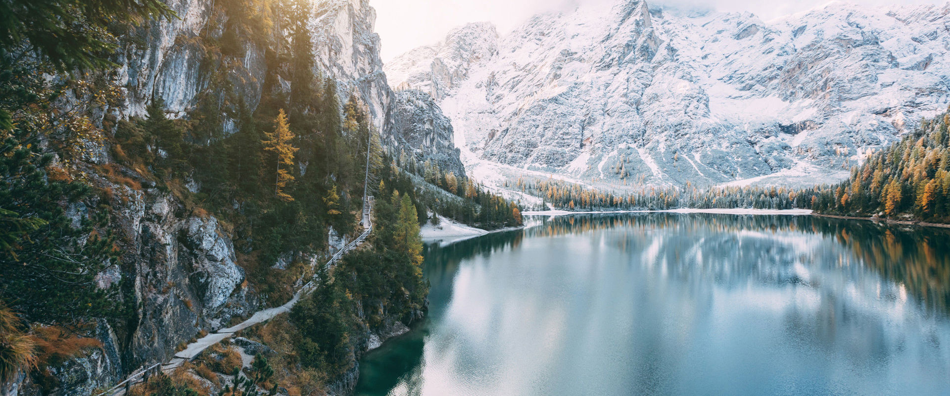 Nature in South Tyrol: Deep blue mountain lake, surrounded by snow-covered mountains and forests