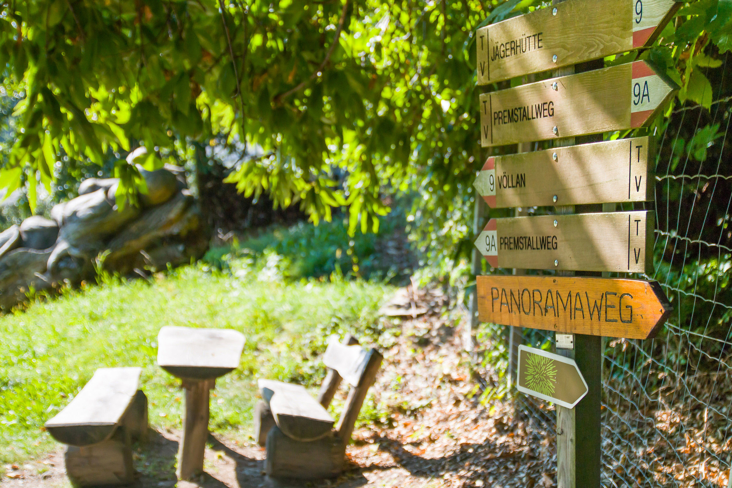 Signpost and bench under a shady tree.