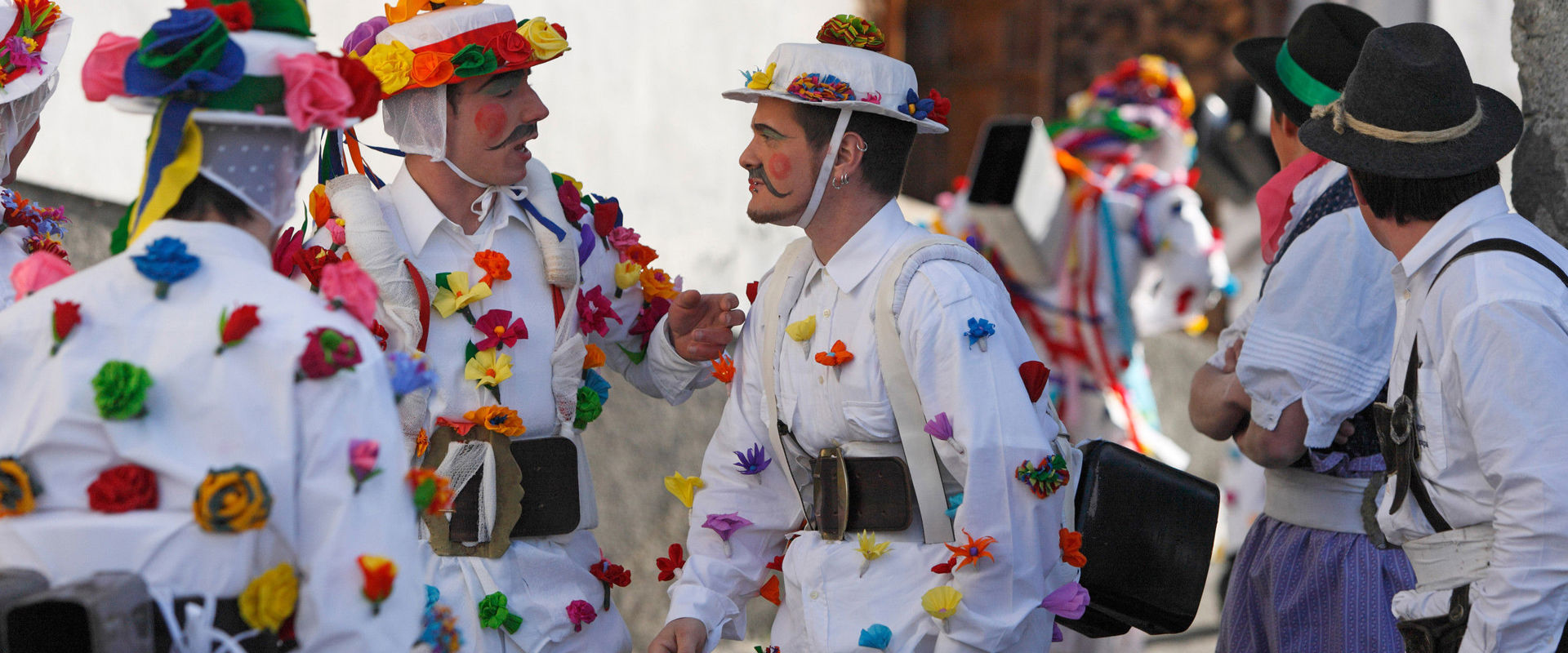Zusseln run Men dressed in white with colourful meshes and flowers. They wear cowbells around their bellies.