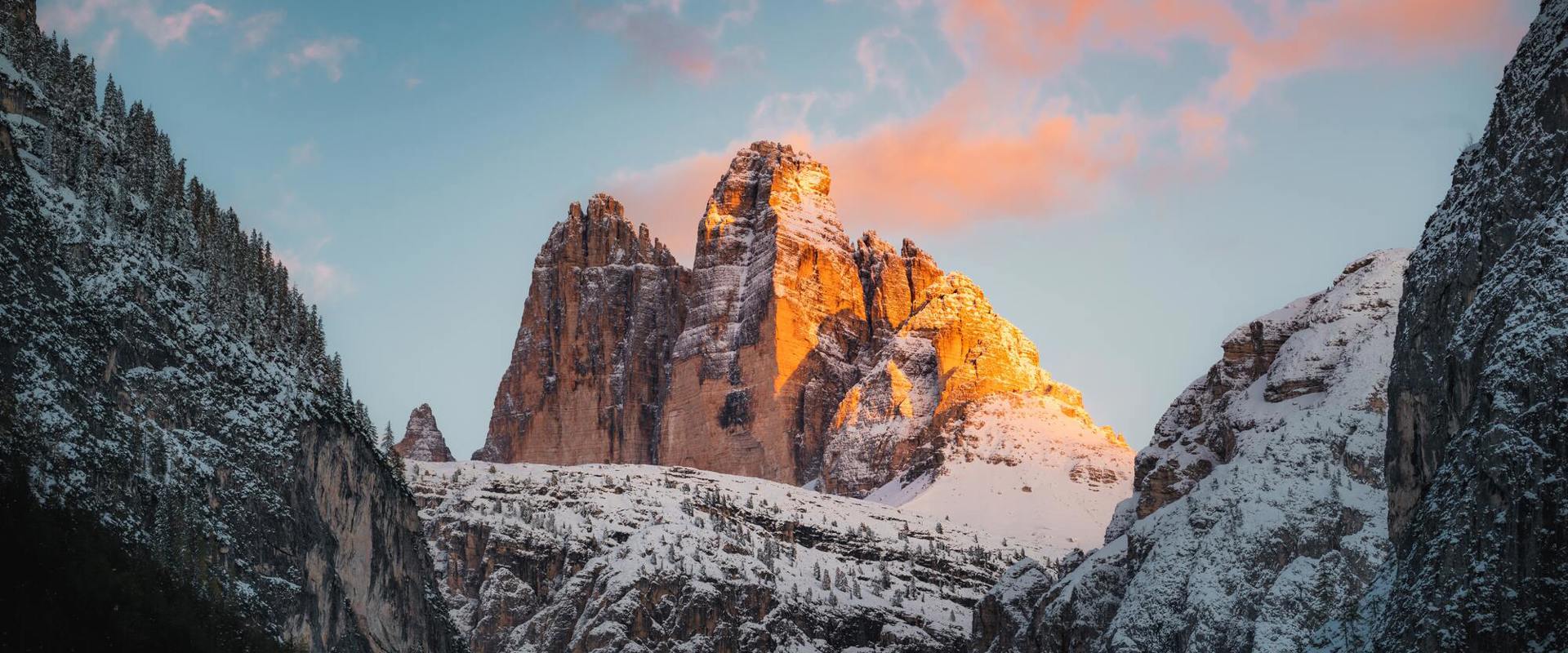Opening hours of the toll road to the Auronzo hut during winter. The three Peaks snow-covered at sunset.