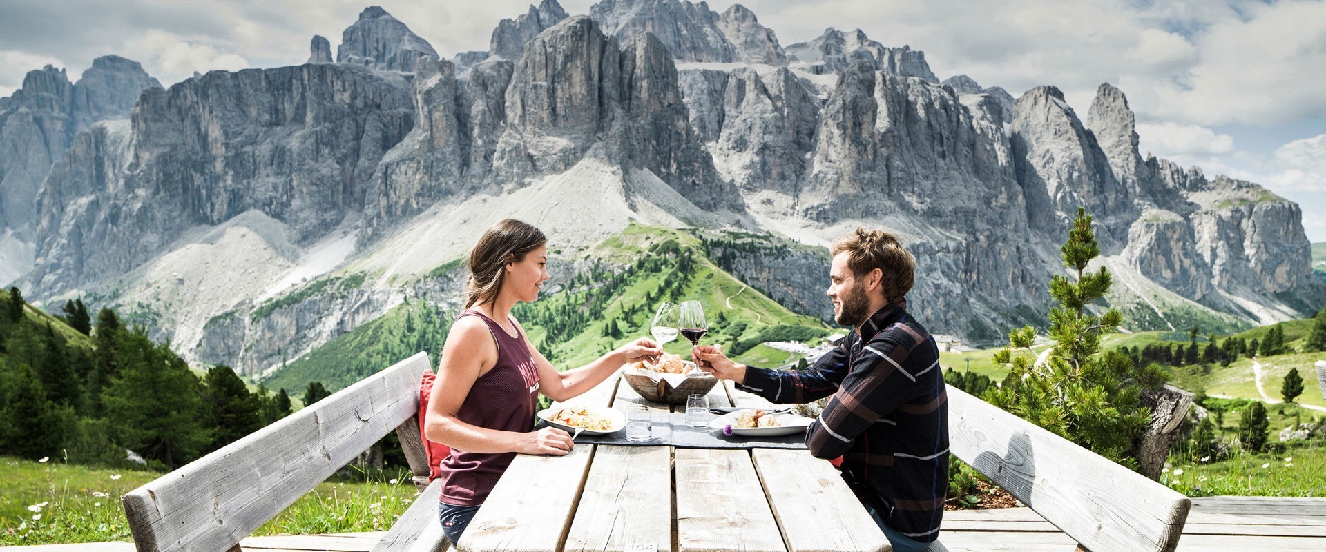 Couple drinking wine & eating on a terrace in the Dolomites