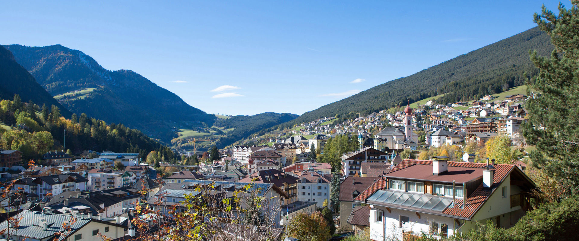 Village between mountain slopes, under a bright blue sky