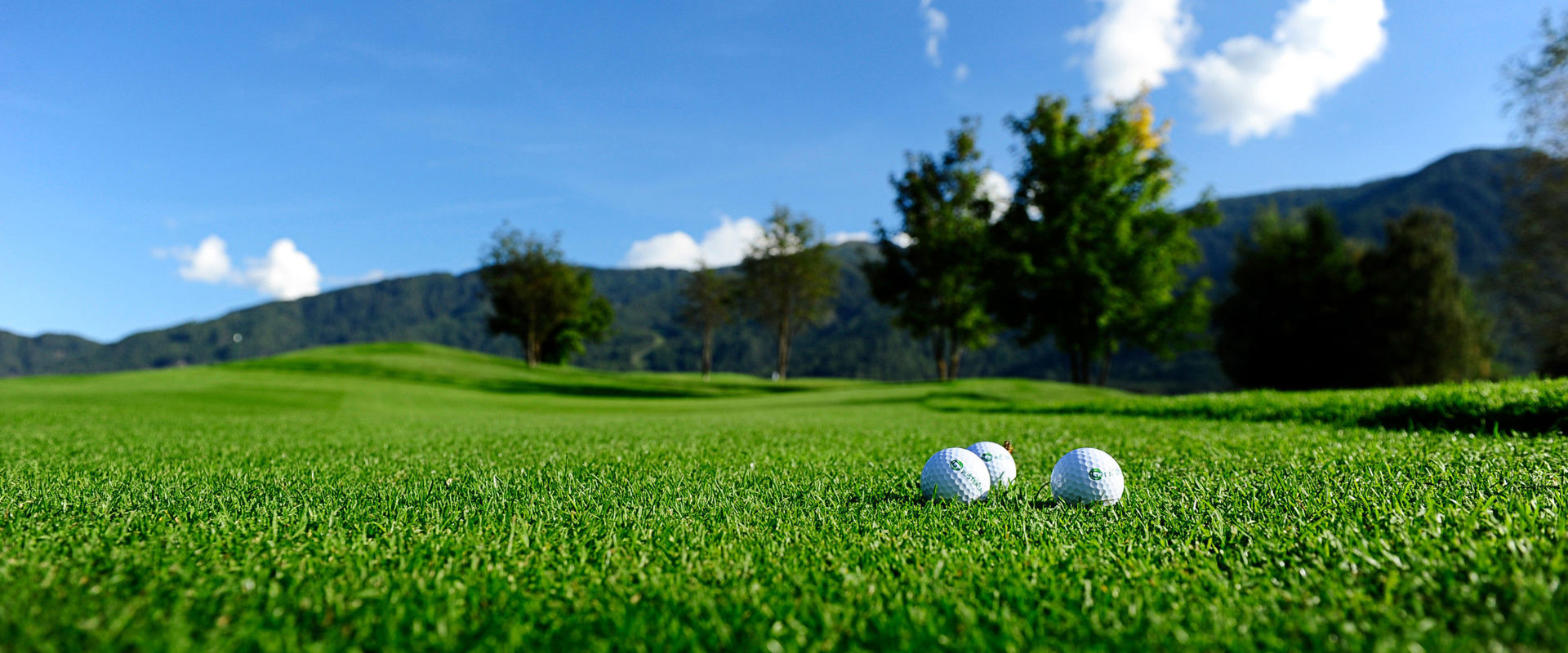 Golf course 3 golf balls lie in the middle of the meadow on the golf course.