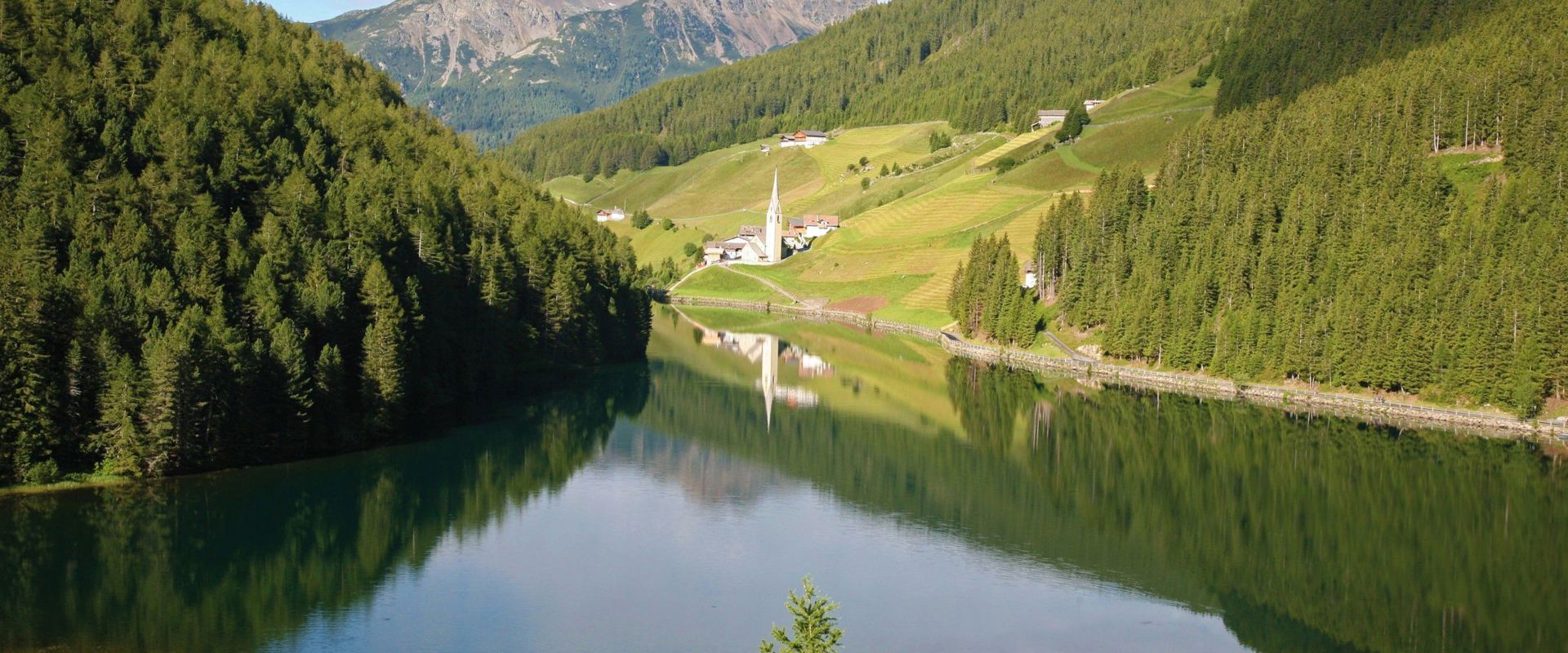 Idyllically situated Lake Durnholz with mountain panorama and view of a small church.