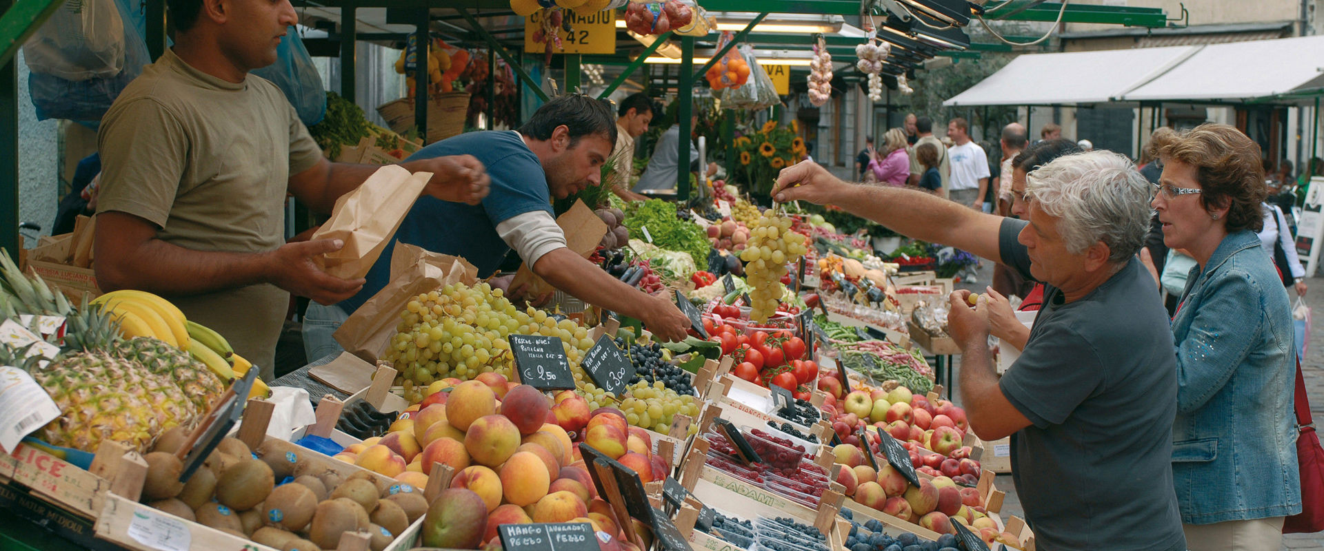 People buy some fresh fruits at the market in the city centre.