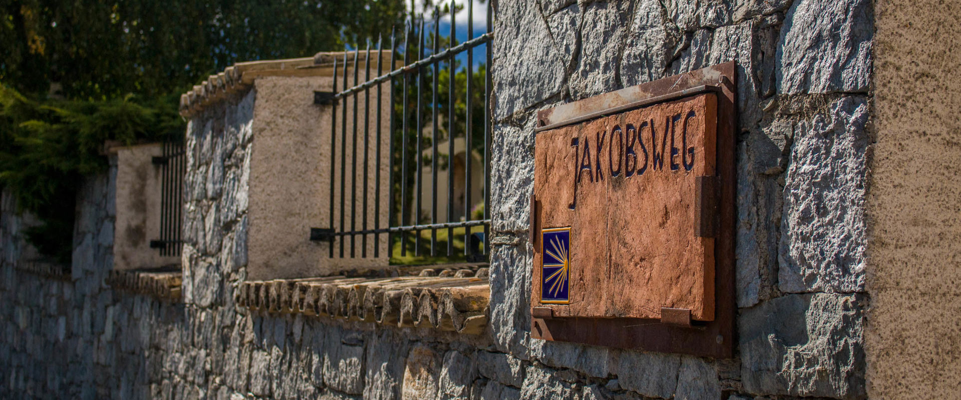 The Way of St James through South Tyrol. Clay sign for the Way of St James on a stone wall.