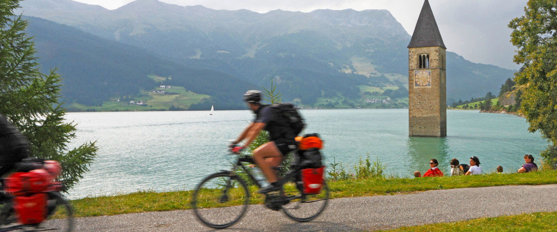 Cyclist rides past Lake Reschen.
