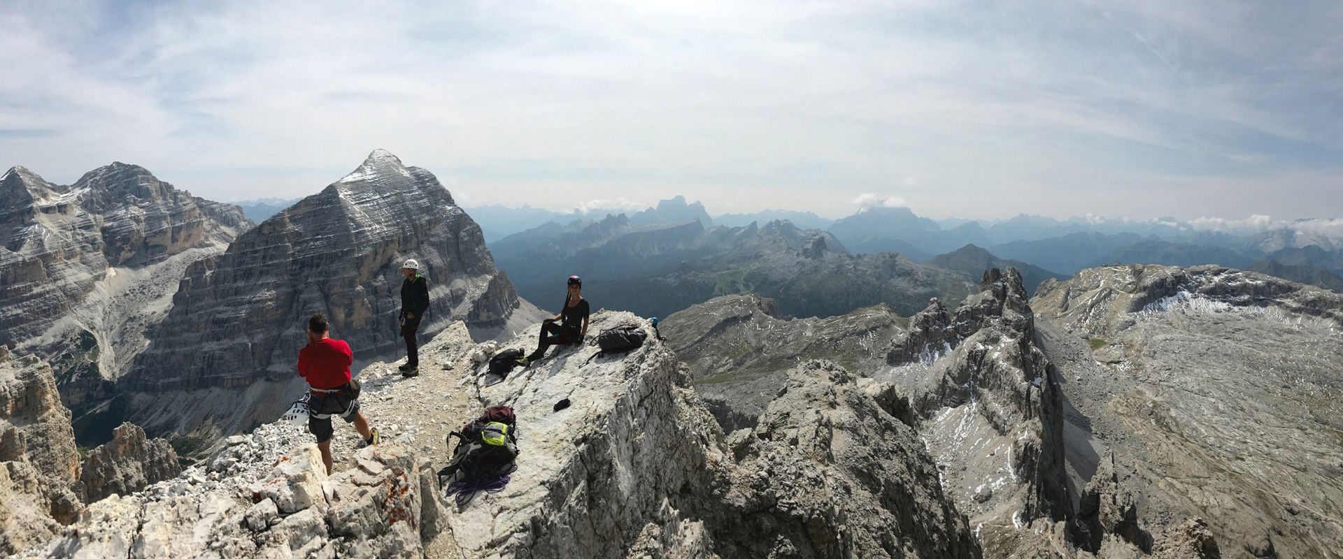 Tomaselli via ferrata in the Dolomites. A group of climbers is sitting on the summit and is having a rest.