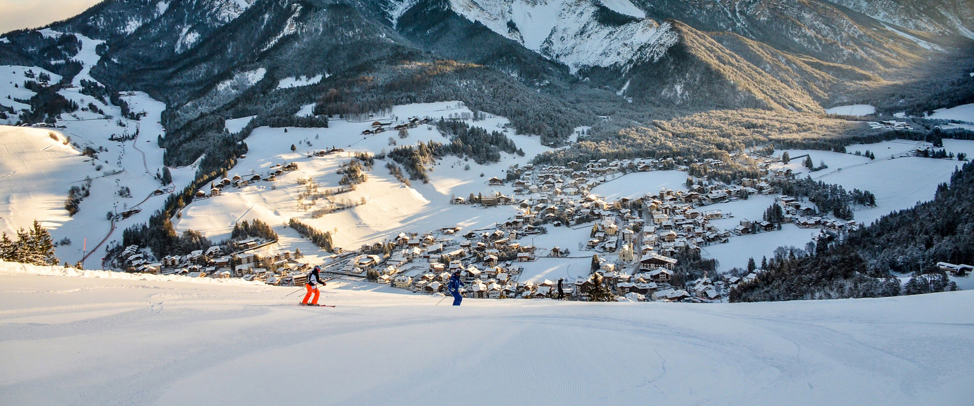 St. Vigil in Enneberg Skiers on slope in St. Vigil in Enneberg with the Dolomites in the background