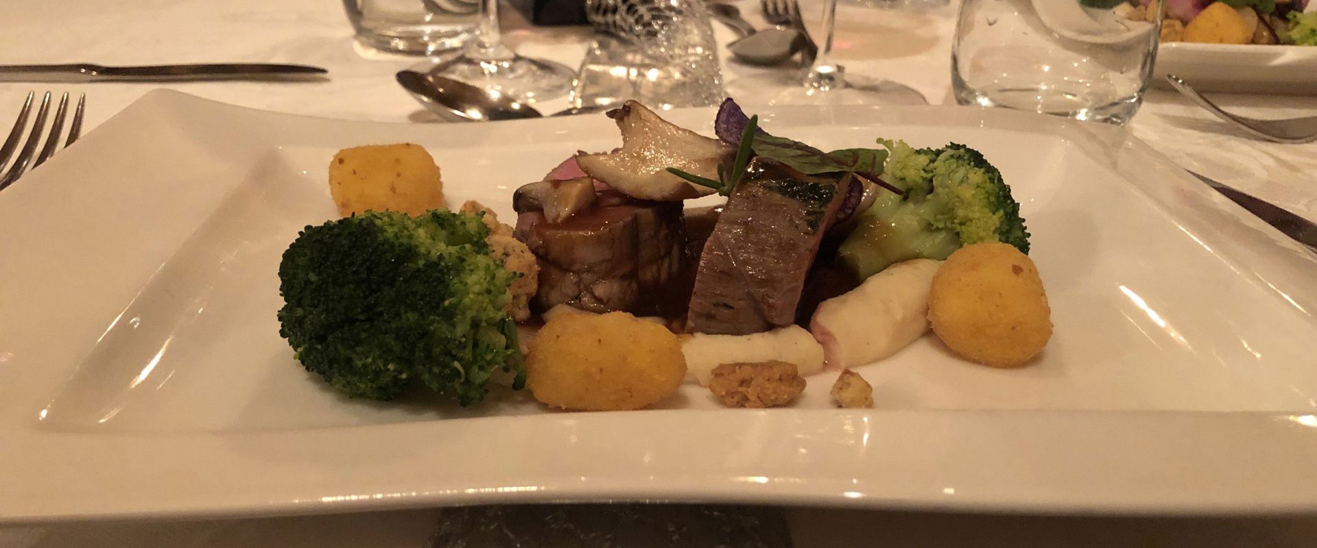 Deer in cranberry sauce is served on a laid table.