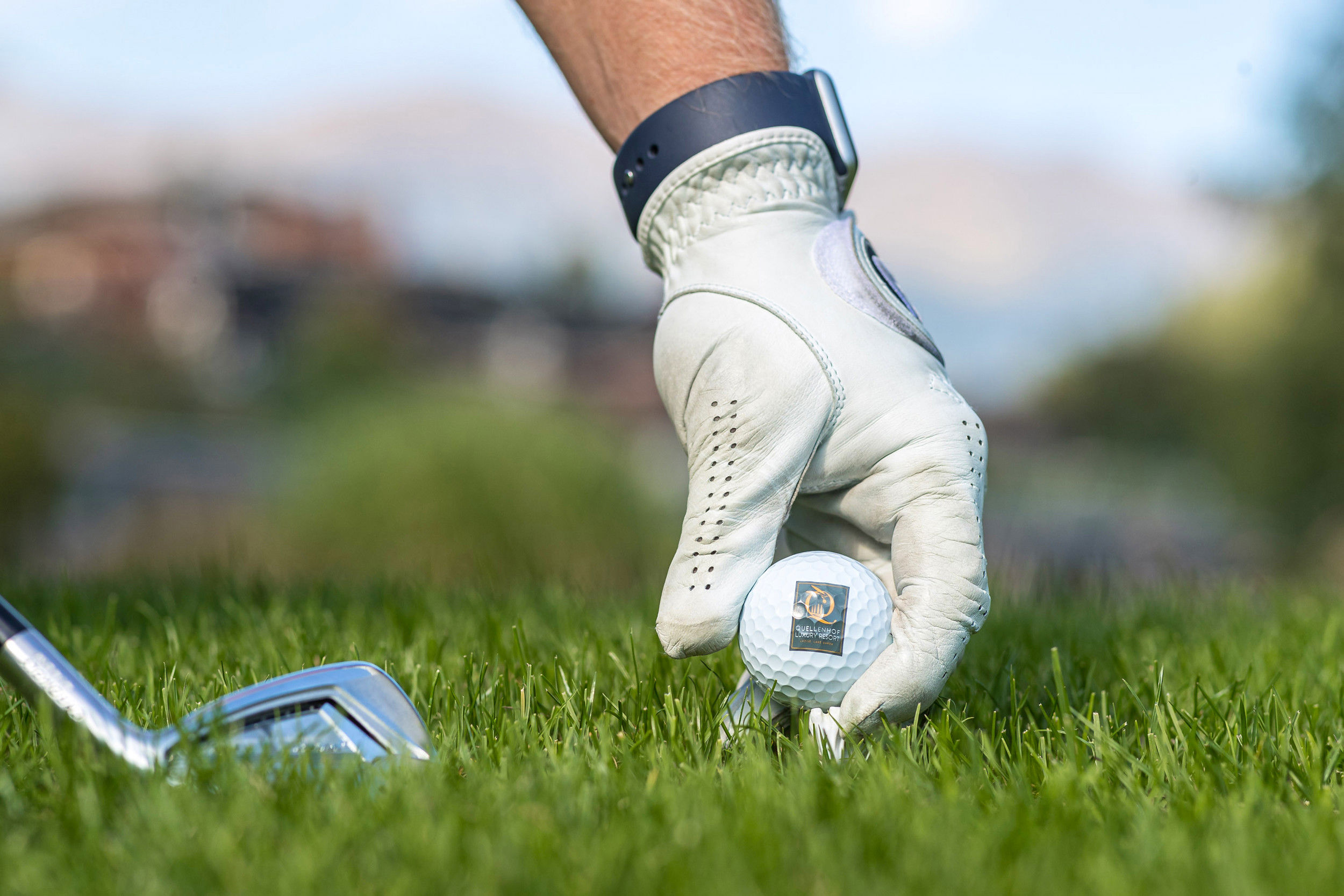 Hand places the golf ball on the grass for the tee shot.