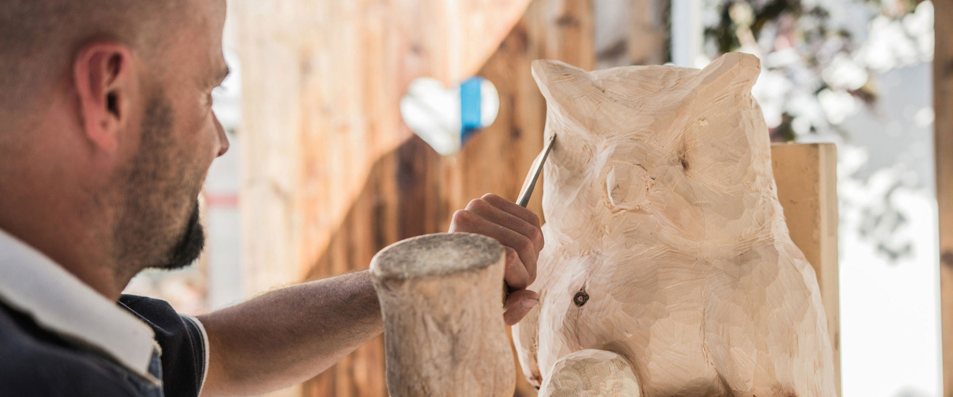 Woodcarver Woodcarver holds hammer and chisel and carves an owl.