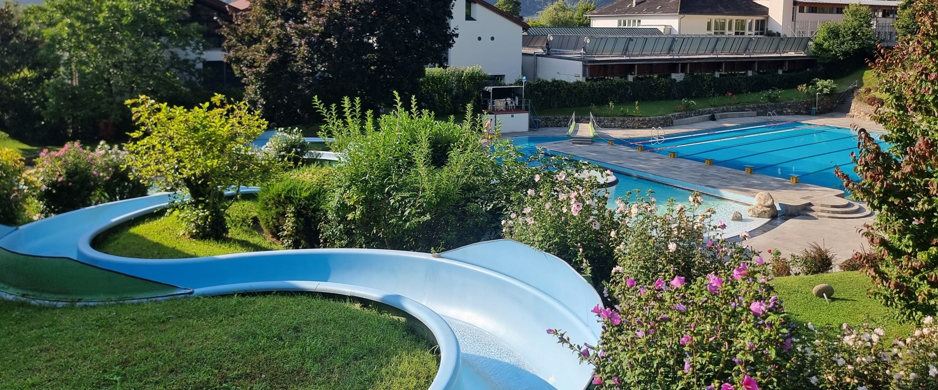 Outdoor area of the Erlebnistherme Naturns Outdoor swimming pool with water slide in the middle of vineyards.