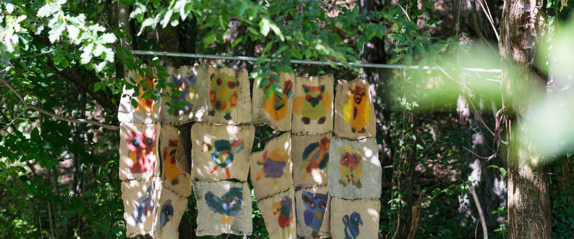 Felt art trail between Tisens and Prissian. Felt figures hang on a pole between the trees in the forest.