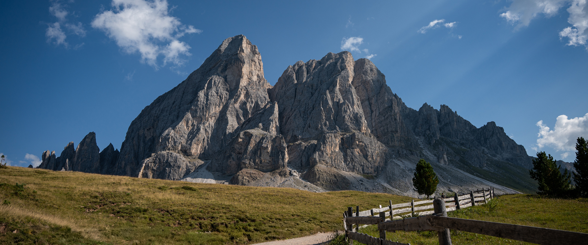 Peitlerkofel at the Würzjoch pass A striking mountain massif rises at the Würzjoch pass behind an alpine meadow with a few trees and a wooden fence