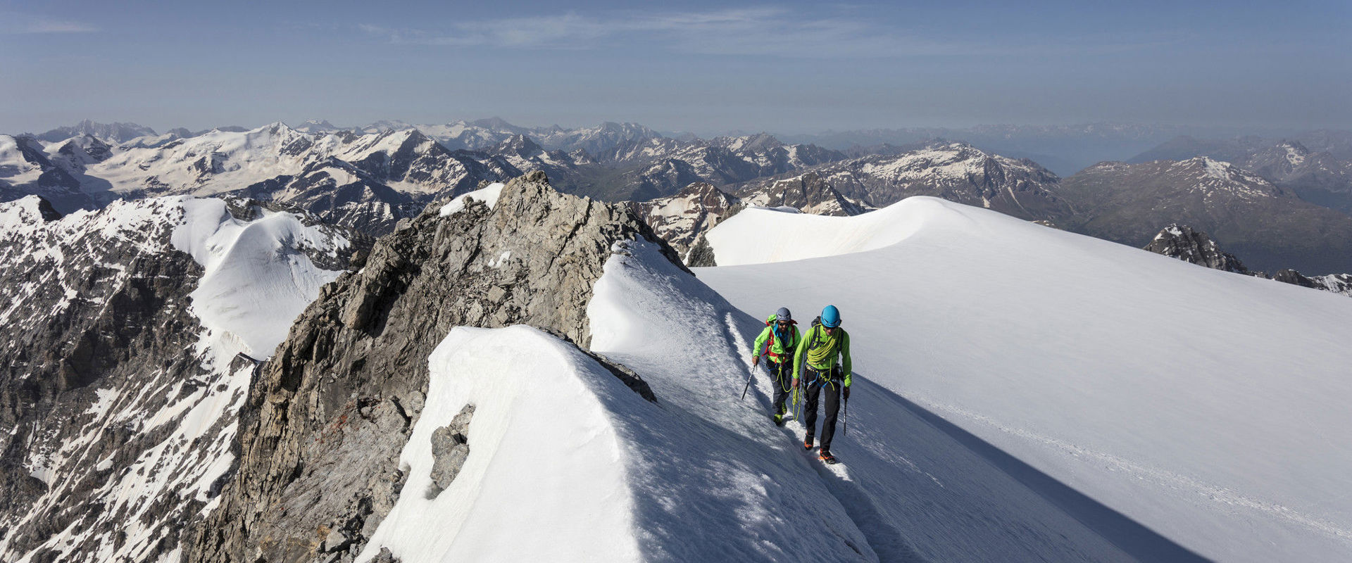 Two athletes reach the mountain summit on touring skis.
