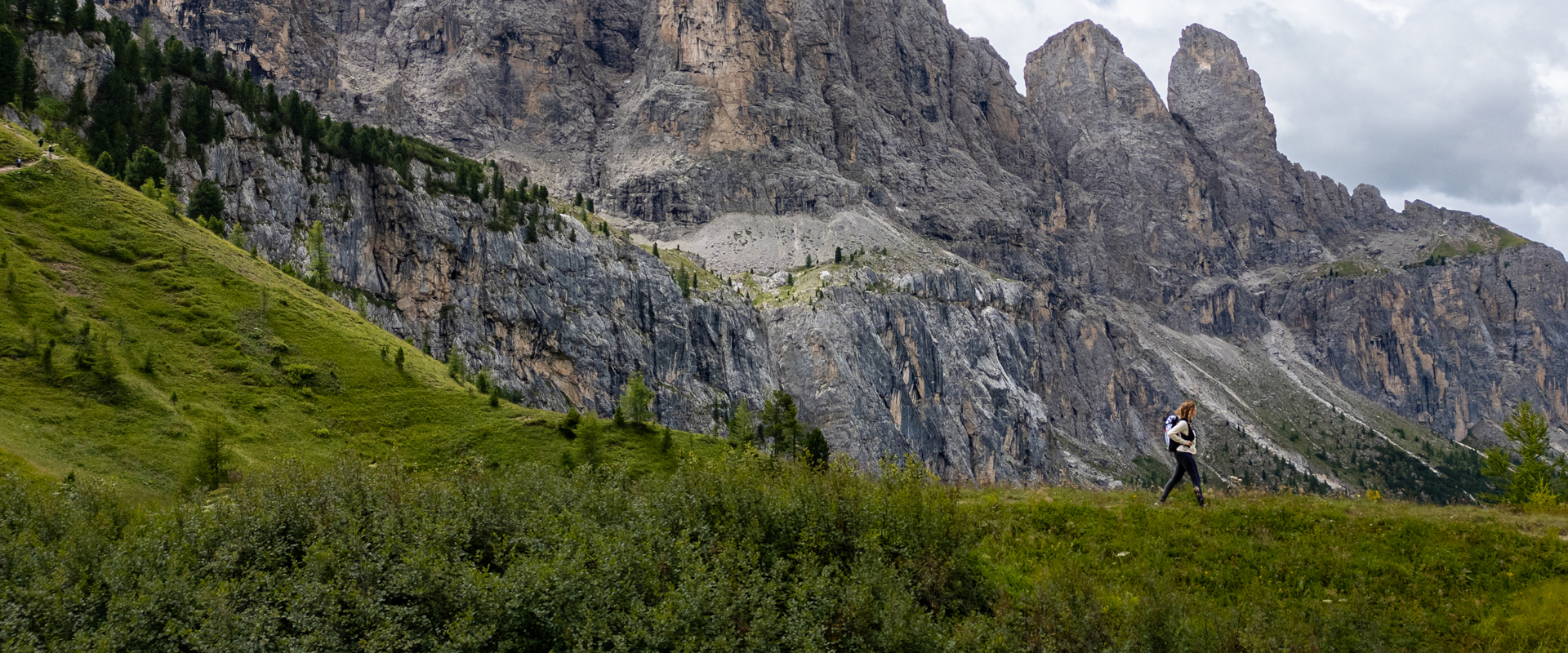 Grödnerjoch Pass Hiker on a mountain meadow with rock faces in the background