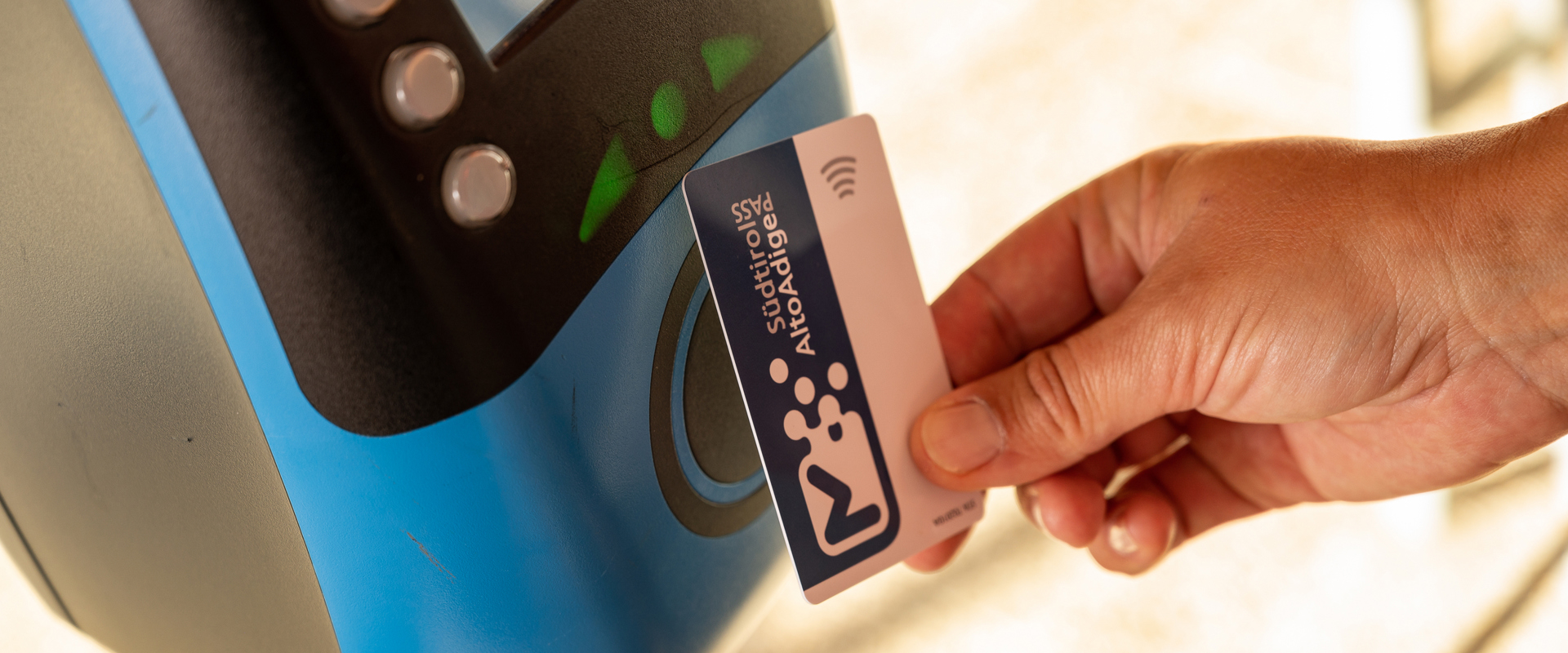 Hand holds public transport card to a device for validation