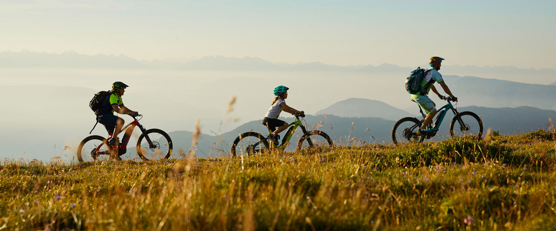 3 people ride up the mountain on an e-bike.