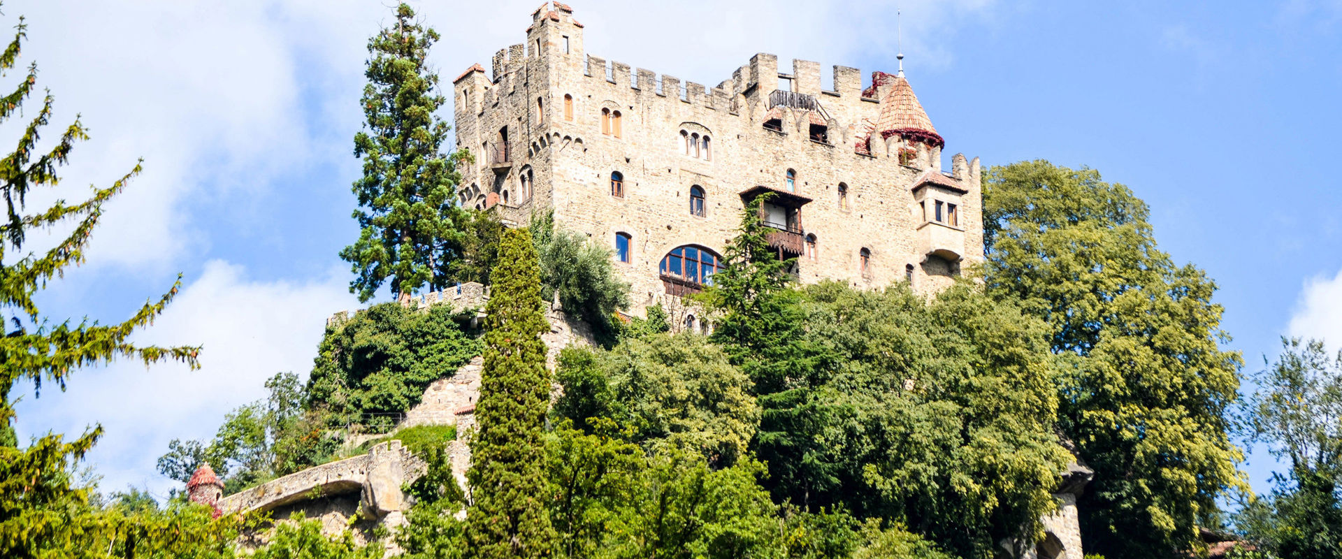 Brunnenburg Castle surrounded by tall trees.