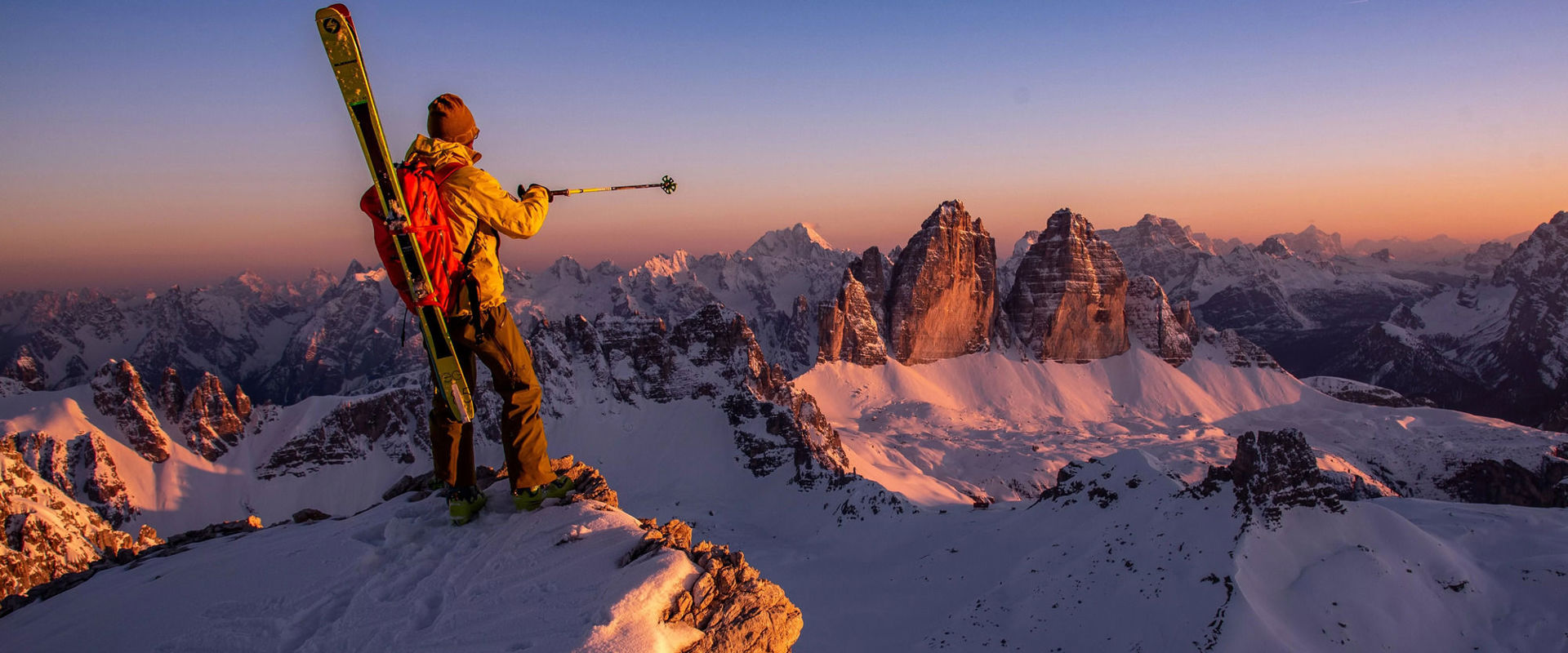 Alpine School Three Peaks in Sexten Ski mountaineer admires the Three Peaks after climbing to the summit with his skis on his shoulders.