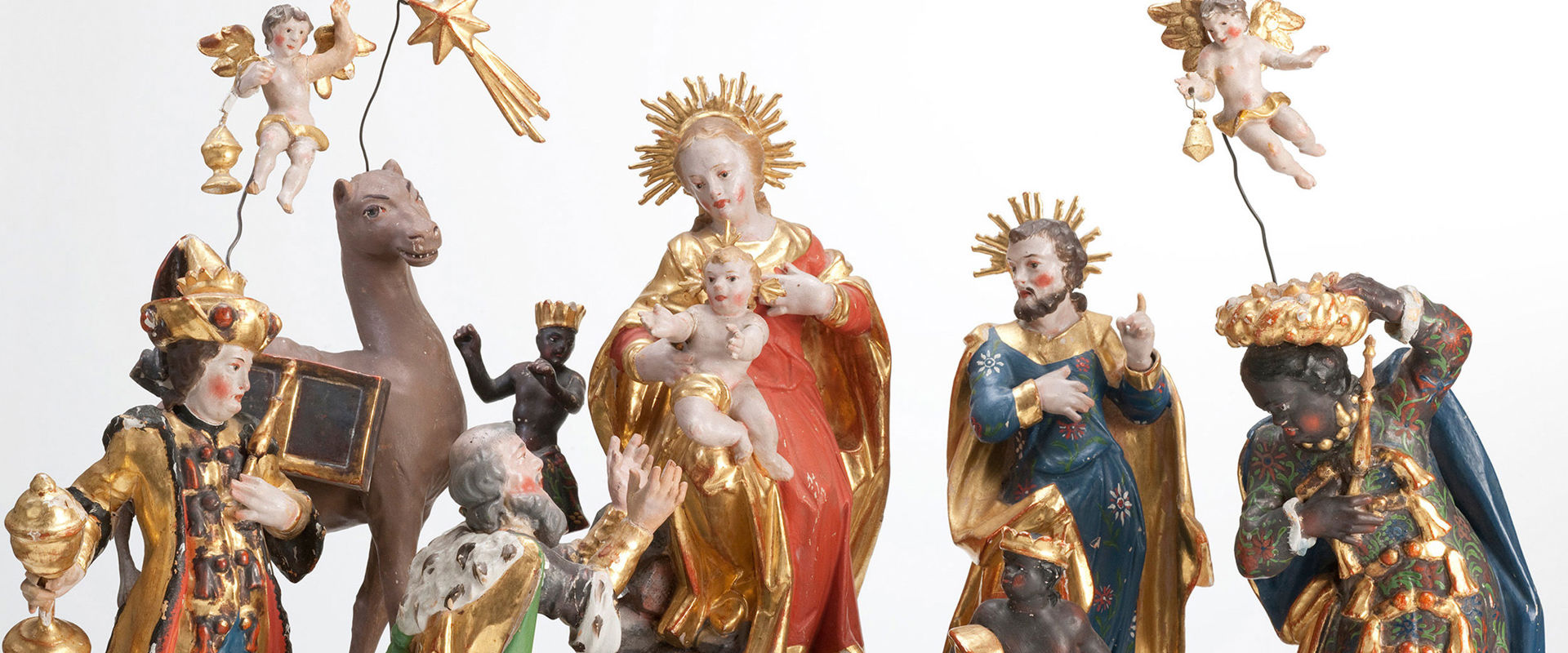 Carved figures of a nativity scene. In the centre Mary and Joseph with the Christ child.