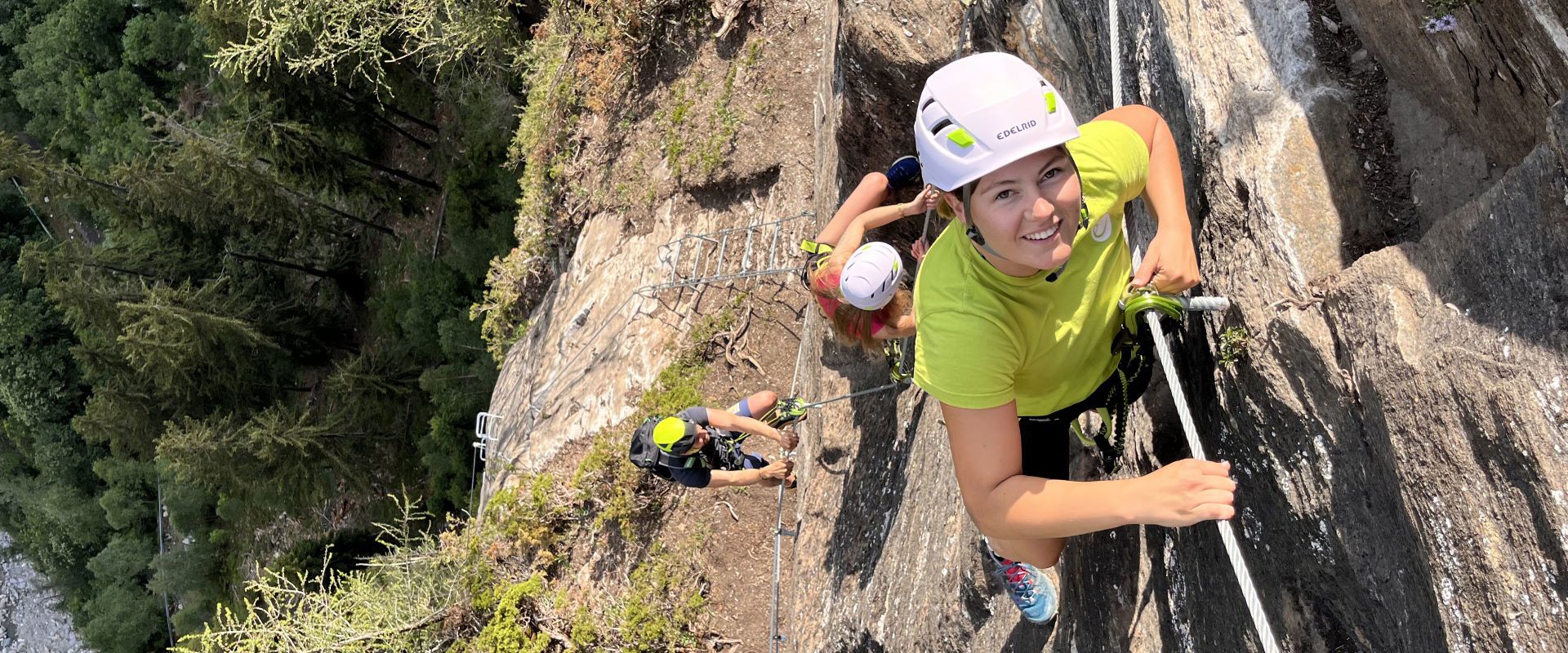 A group climbs the vertical wall of the Ölberg via ferrata in Pfitsch.