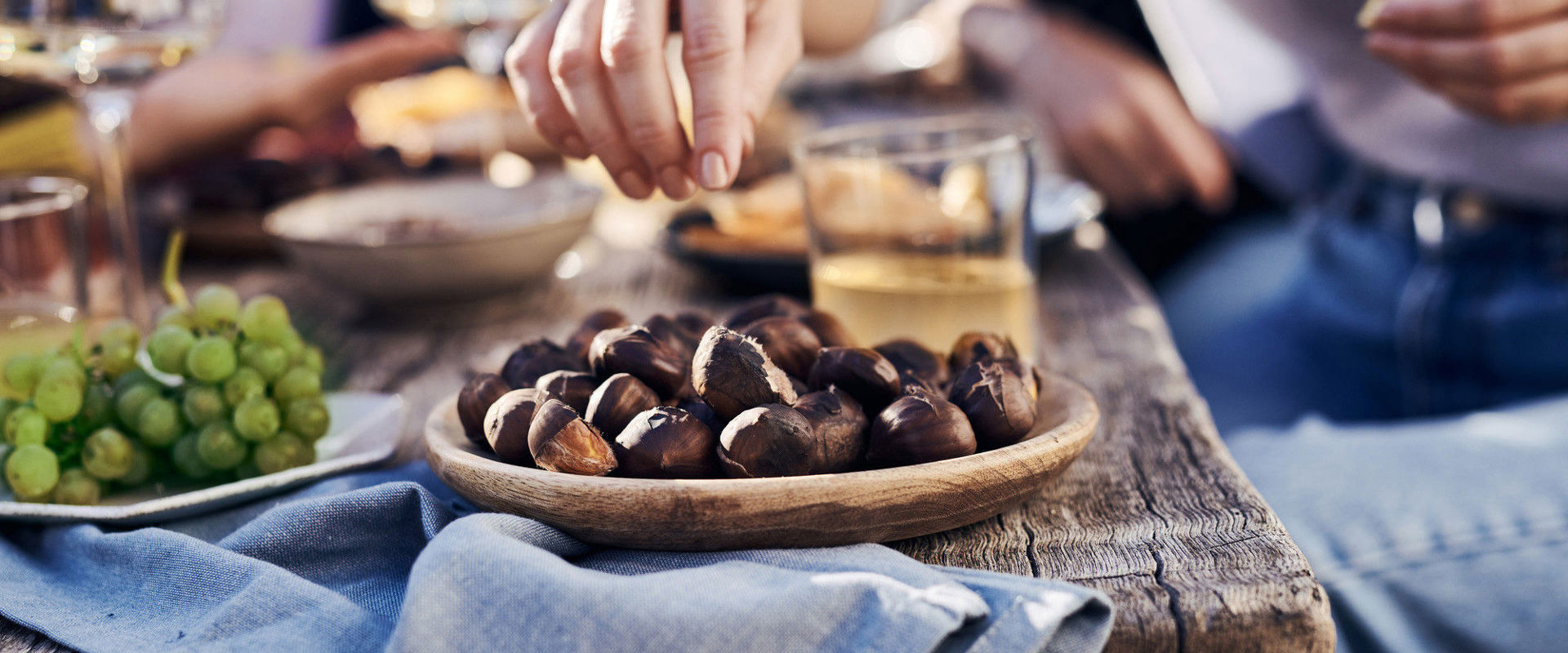 Wooden table with grapes, chestnuts and wine.